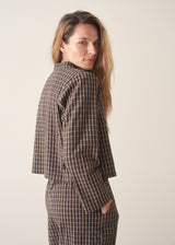 A woman wearing a dark brown check cropped jacket with matching barrel leg trousers and a white t-shirt