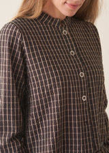 A woman wearing a dark brown check cropped jacket with matching barrel leg trousers and a white t-shirt