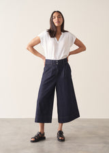 Woman wearing a white top and dark navy wide-leg denim cullottes