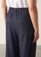 Woman wearing a white top and dark navy wide-leg denim cullottes