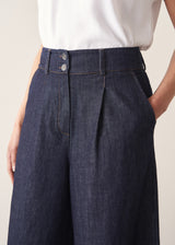Woman wearing a white top and dark navy wide-leg denim cullottes