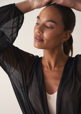 Close up of women wearing a long sleeve sheer sparkle draped top with cream satin camisole