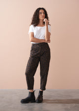 Woman wearing a white t-shirt and leopard print barrel leg trousers against a beige background