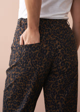 Leopard print pants worn by a person on a beige background