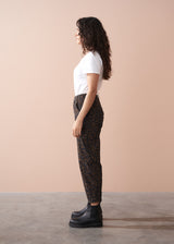 Woman wearing a white t-shirt and leopard print barrel leg trousers against a beige background
