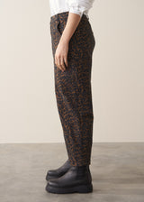 Woman wearing a white shirt and leopard print barrel leg jeans against a plain background