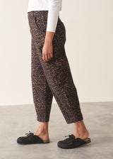 Woman wearing dark brown leopard print barrel leg trousers and a long sleeve white top