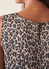 Woman wearing sleeveless satin leopard print dress with black boots and a black suede jacket