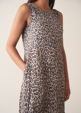 Woman wearing sleeveless satin leopard print dress with black boots and a black suede jacket
