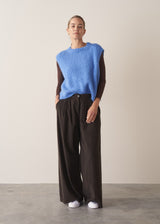 Woman wearing brown, wide leg corduroy trousers and a cornflower blue sleeveless sweater