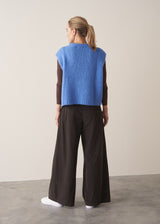 Woman wearing brown, wide leg corduroy trousers and a cornflower blue sleeveless sweater