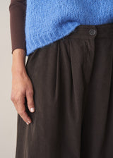 Woman wearing brown, wide leg corduroy trousers and a cornflower blue sleeveless sweater