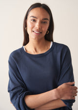 Woman wearing navy blue sweatshirt with drawstring and blue jeans