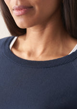 Woman wearing navy blue sweatshirt with drawstring and blue jeans