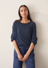 Woman wearing navy blue sweatshirt with drawstring and blue jeans