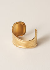 Gold cuff bracelet on a beige background