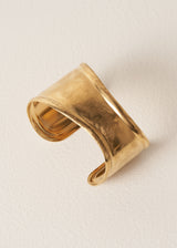 Gold cuff bracelet on a beige background