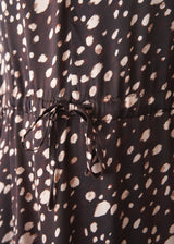 A woman wearing a brown polka dot doe print midi dress with long sleeves.