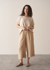 Woman wearing oatmeal sleeveless knitted top with wide leg linen trousers in oatmeal beige