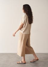 Woman wearing oatmeal sleeveless knitted top with wide leg linen trousers in oatmeal beige