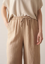 Woman wearing oatmeal sleeveless knitted top with wide leg linen trousers in oatmeal beige
