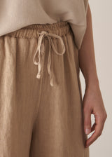 Woman wearing oatmeal sleeveless knitted top with wide leg linen trousers in oatmeal beige