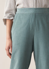 Woman wearing corduroy tapered trousers in aqua and pale checked shirt