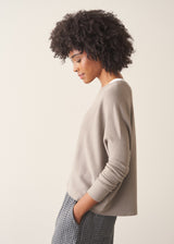 Woman wearing light grey fine knit sweater with checked linen trousers