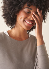 Woman wearing light grey fine knit sweater with checked linen trousers