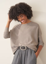 Woman wearing light grey fine knit sweater with checked linen trousers