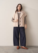 Woman wearing long sleeve stone-grey fine knit sweater with dark blue denim trousers