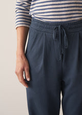 Woman wearing dark blue-grey cotton joggers and navy and cream stripe top
