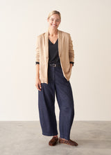 Woman wearing black lightweight knit sweater with blue jeans and a beige jacket
