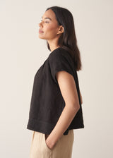 Woman wearing black linen boxy top with oatmeal linen trousers