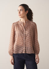 Woman wearing brown floral print top with dark blue jeans