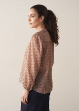 Woman wearing brown floral print top with dark blue jeans