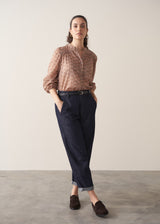 Woman wearing brown floral print top with dark blue jeans