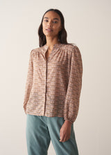 Woman wearing a brown floral blouse against a plain background