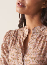 Woman wearing a brown floral blouse against a plain background