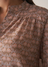 Woman wearing a brown floral blouse against a plain background