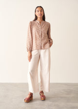A woman wearing a long-sleeve button-up shirt with a small beige and brown floral pattern.