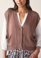 Woman wearing brown knitted waistcoat, a white cotton top and leopard print trousers
