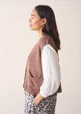 Woman wearing brown knitted waistcoat, a white cotton top and leopard print trousers