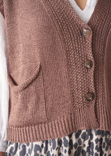 Woman wearing brown knitted waistcoat, a white cotton top and leopard print trousers