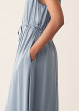 Woman wearing a dusky blue satin midi dress standing against a plain background