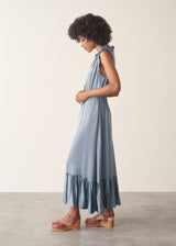 Woman wearing a dusky blue satin midi dress standing against a plain background