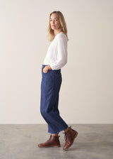 Woman wearing blue barrel leg jeans with a white cotton embroidered top.