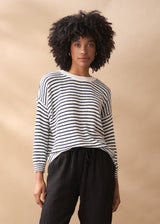 Woman wearing striped light knit sweater with crew neck, and black trousers