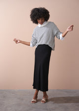 Woman wearing a light knit stripe sweater with white shirt and black skirt