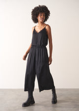 Woman wearing black satin wide leg cropped trousers against a plain background